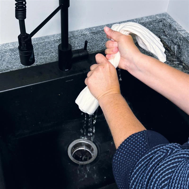 Person cleaning a kitchen sink with a white mighty mat